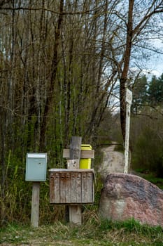 Spring landscape with rural mailbox. Old mailbox at rural roadside next to the big stone in Latvia.