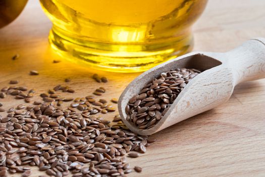 Linseed on a wooden table, with flax seed oil in the background