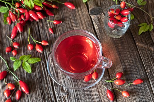 A cup of rose hip tea on a wooden table, top view