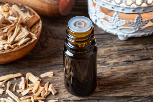 A bottle of essential oil with cedar wood chips