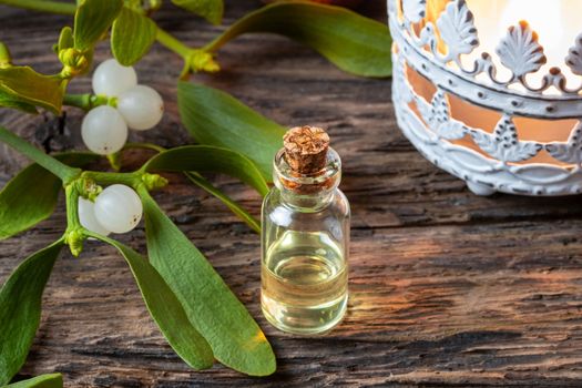 A bottle of essential oil with fresh mistletoe