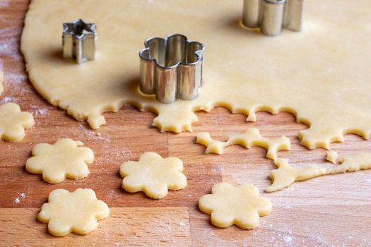 Cutting out flower shapes from rolled out dough to prepare traditional Linzer Christmas cookies