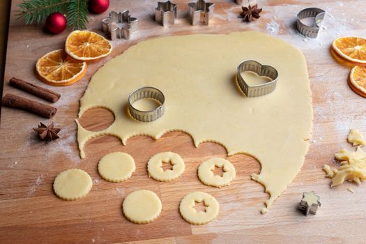 Cutting out shapes from rolled out dough to prepare traditional Linzer Christmas cookies