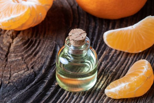 A bottle of citrus essential oil with fresh tangerines