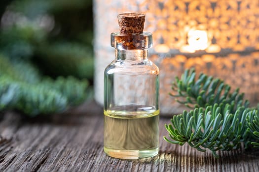 A bottle of essential oil with fresh fir branches