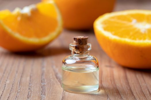 A bottle of citrus essential oil with fresh oranges in the background