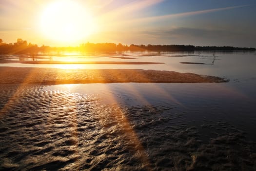 The sandy coast at the river at sunset