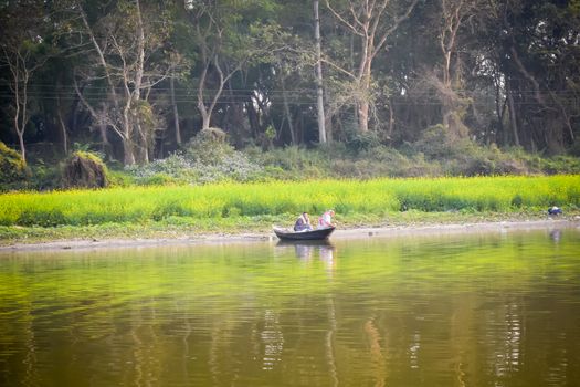 Kumari river side, Mukutmanipur, Bankura, West Bengal India December 15, 2018: Fisherman sitting on a wooden boat in evening time. A beautiful landscape of rural Indian coastal village life.