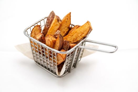 French fries in a metallic stainless steel basket on white