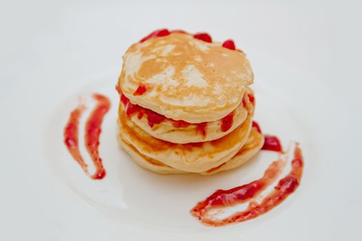 Pancakes with strawberry jam white plate. Selective focus