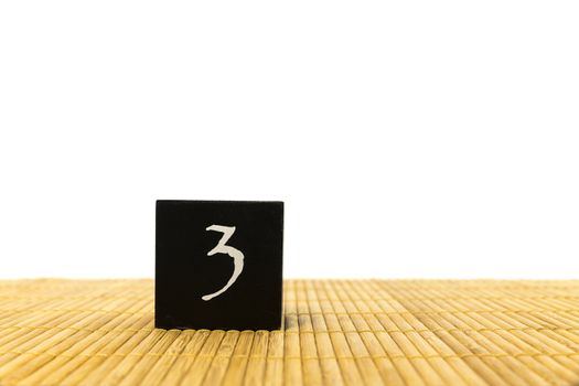 black number 3 block on bamboo underground and with isolated white background