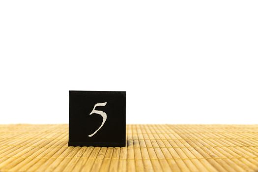 black number 5 block on bamboo underground and with isolated white background