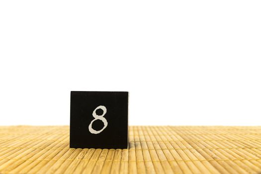 black number 8 block on bamboo underground and with isolated white background