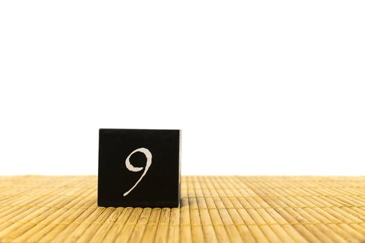 black number 9 block on bamboo underground and with isolated white background