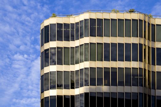 A modern glass and metal building of unusual design with a curved facade and a roof terrace.