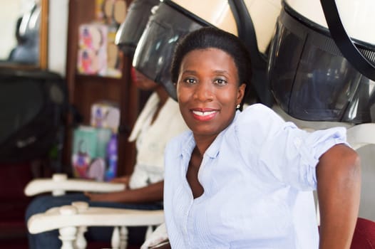 smiling young woman sitting at the hair salon looking in the camera.