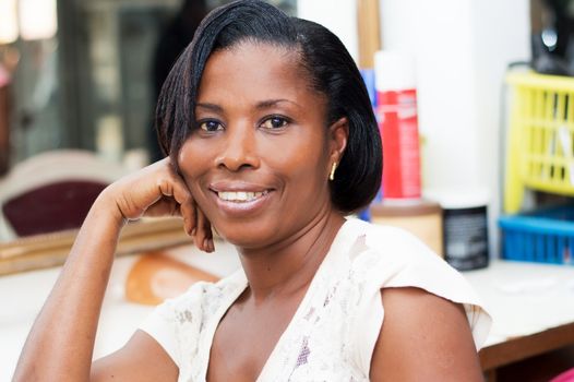 This beautiful smiling woman sitting at the hair salon looking at the camera.