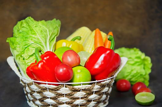 fresh vegetables and fruits in wicker basket over wooden background