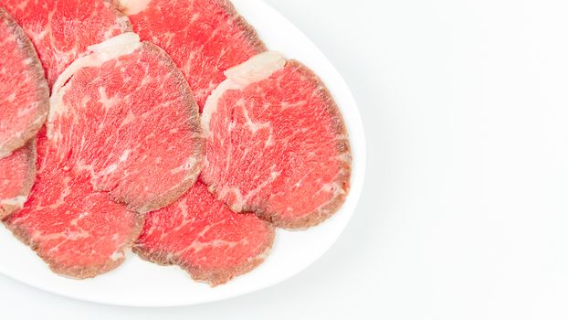 Top view of some raw beef on a plate over white background