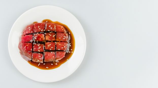 Top view of some raw beef with sauce on a plate over white background