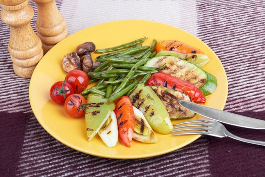 grilled vegetables on a yellow platefnd fork fnd knife