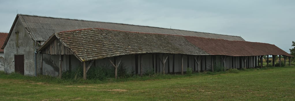 Long shed next to stable on a large field, side view