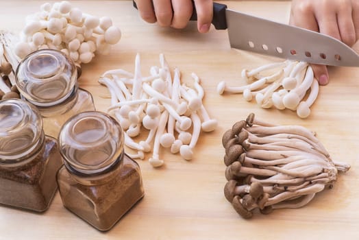 A set of mushroom ingredients on a wooden board.White beech mushrooms or Shimeji mushroom . Small white and brown mushrooms on the table.