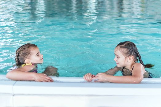 Two little girls having fun in the pool.Two little girls swim in the pool. Two friends in the pool.