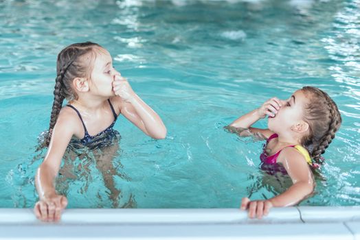 Two little girls having fun in the pool.Two little girls swim in the pool. Two friends in the pool.
