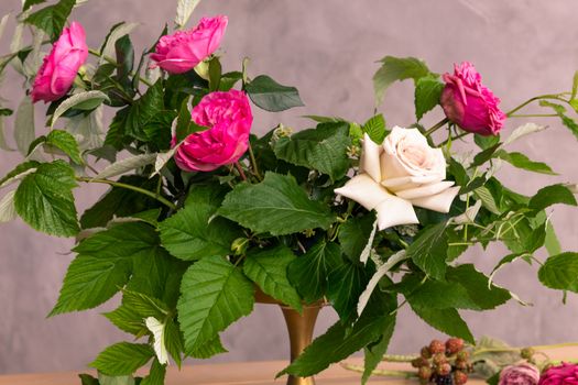 On the wooden surface laid out tools for flower bouquets: scissors, roses, colored ribbon, roses.