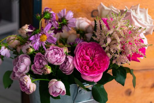 On the wooden surface laid out tools for flower bouquets: scissors, roses, colored ribbon, roses.