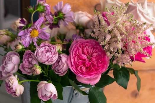 On the wooden surface laid out tools for flower bouquets: scissors, roses, colored ribbon, roses.