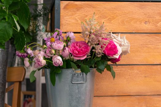 On the wooden surface laid out tools for flower bouquets: scissors, roses, colored ribbon, roses.