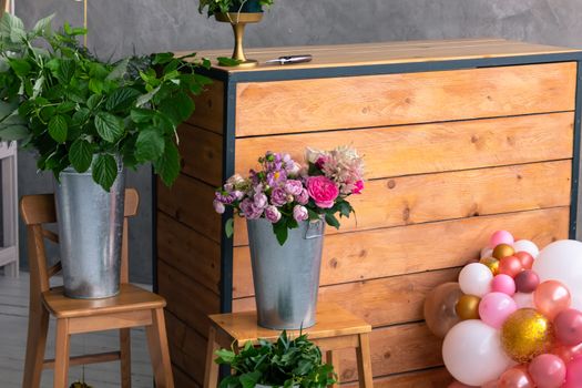 On the wooden surface laid out tools for flower bouquets: scissors, roses, colored ribbon, roses.