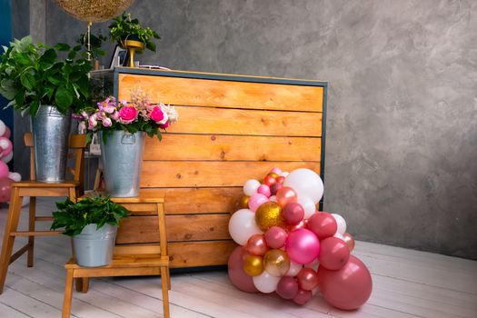 On the wooden surface laid out tools for flower bouquets: scissors, roses, colored ribbon, roses.