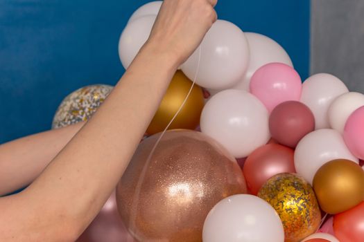 Beautiful girl makes a bouquet of balloons for the holiday.