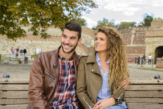 Attractive couple in love enjoying moments of happiness on the bench in city park