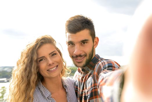 Two lovers taking a selfie photo near the river while enjoying the moments of happiness and love