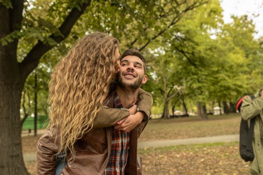 Attractive woman kissing her boyfriend in the public park