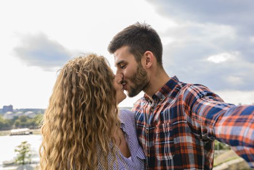 Attractive and modern lovers kissing in the nature