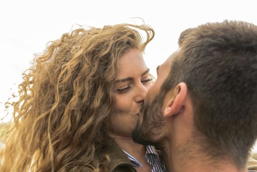 Attractive and modern lovers kissing in the nature