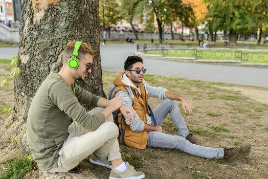 Two friends relaxing under the tree in the public park