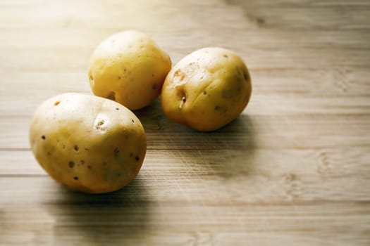 Three Raw potatoes on a wooden cutting board. Fresh organic potato.