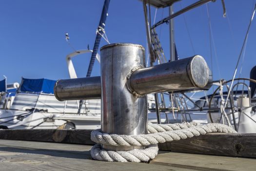 stainless steel bollard on the dock against background of yachts