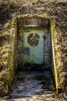Rusty door with a lock on a bunker covered with grass and moss