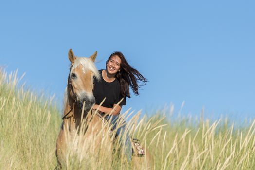 eighteen year old girl a haflinger horse posing with the dunes as background