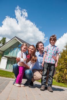 Happy family of parents and children in front of their house outdoors