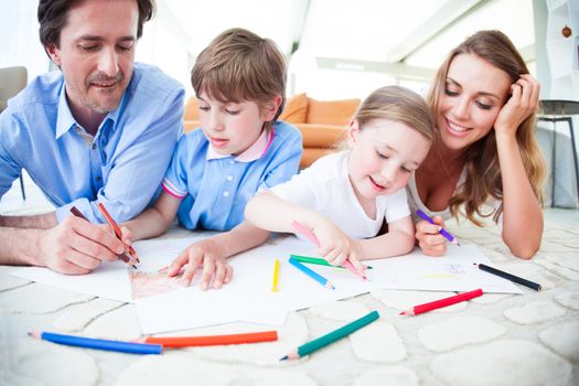 Charming family with children drawing together on the floor in a living room