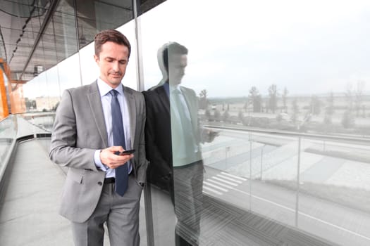 Businessman using smart phone at the balcony of office building