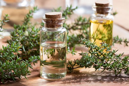 A bottle of thyme essential oil with fresh thyme leaves on a wooden background